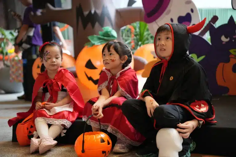 Children in Red Riding Hood and devil costumes beside the pumpkins