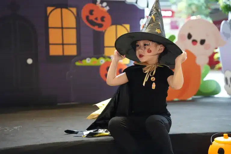 A little witch posing on the Halloween stage