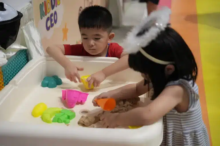 Two children playing with coloured sand at the Kiddie CEO table